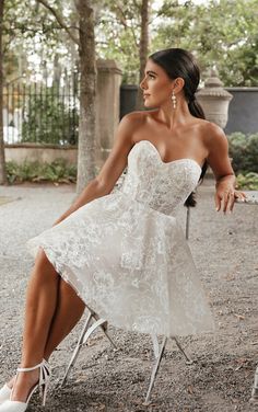 a woman in a white dress sitting on a chair