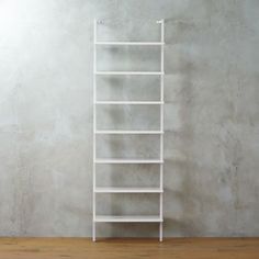 a tall white shelf sitting on top of a hard wood floor next to a wall