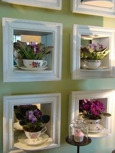 four framed pictures on the wall with flowers in pots and teacups inside them