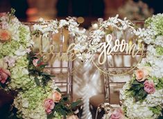 two chairs decorated with flowers and greenery are sitting next to each other on the table