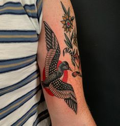 a man's arm with a bird and flower tattoo design on the left arm