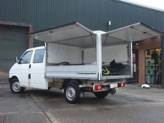 a white truck is parked in front of a building with two open doors on it