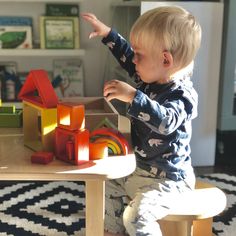 a toddler playing with wooden blocks in a playroom