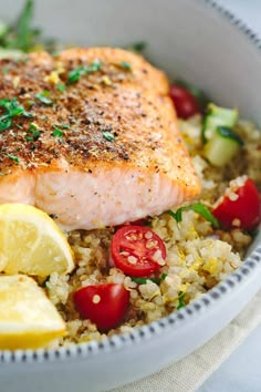 a close up of a bowl of food with salmon, rice and veggies