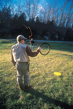 a man holding a black and yellow frisbee on top of a lush green field