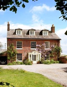 a large red brick house sitting on top of a lush green field