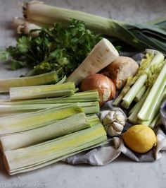 an assortment of vegetables on a table with lemons, onions and celery