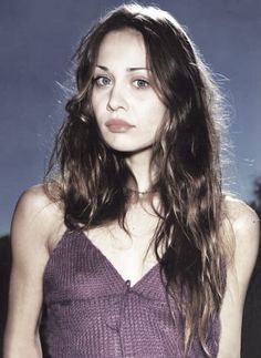 a woman with long hair wearing a purple top