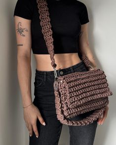 a woman holding a crocheted purse in her right hand and wearing a black t - shirt