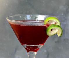 a red drink in a glass with a slice of kiwi on the rim