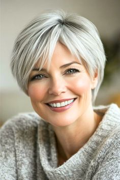 Cropped Piecey Layers Hairstyle on a smiling woman in her 50s with short gray hair.