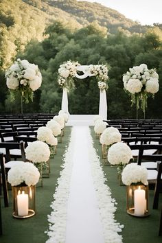 the aisle is lined with white flowers and candles