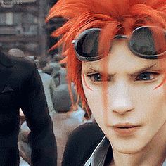 a man with red hair and goggles standing next to another man