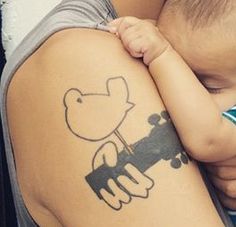 a person holding a small child with a tattoo on their arm and shoulder that has a cartoon character drawn on it