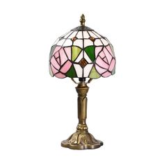 a pink and green stained glass lamp on a brass stand with a white background,