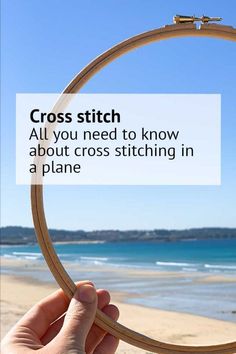 a hand holding a hoop with the words cross stitch all you need to know about cross stitching in a plane