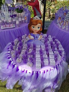 there is a table with purple and white decorations on it that has princesses on it