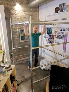 a man standing on top of a metal handrail in a room with lots of clutter