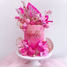 a pink birthday cake decorated with flowers and feathers