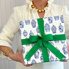 a woman holding a present wrapped in blue and white paper with a green bow on it