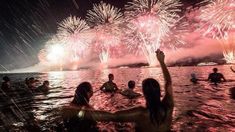 people are swimming in the water with fireworks