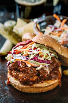 a pulled pork sandwich with coleslaw and slaw on a table next to fries