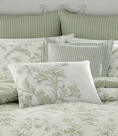 a bed with green and white comforters and pillows on top of it's headboard