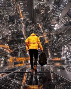 a person in yellow jacket walking on top of a building with city lights behind him