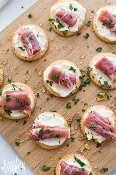 crackers topped with prosciutto, cheese and parsley on a cutting board