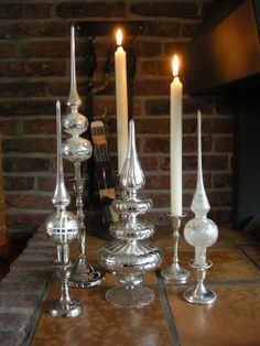 some candles are sitting on a table near a brick wall and a fireplace in the background