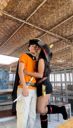 a man and woman dressed up as pirates kissing in front of a wooden ceiling with lights