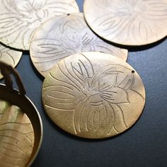 four metal discs with flowers on them and a pair of pliers next to them