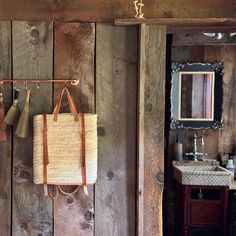 a bag hanging on a wooden wall next to a sink with a mirror above it