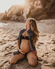 a pregnant woman is sitting on the beach