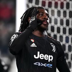 a man with dreadlocks talking on a cell phone in front of a net