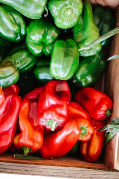 green and red peppers sitting on ice in a container