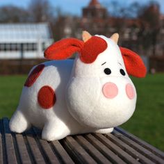 a white and red stuffed animal sitting on top of a wooden bench in a park