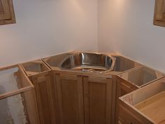 an unfinished kitchen with wooden cabinets and a stainless steel sink in the corner, which is being built