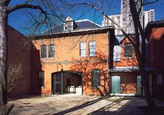 an old brick building in the middle of a street with trees and buildings behind it