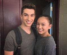 a young man and woman standing next to each other in front of a door smiling at the camera