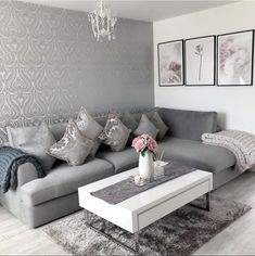 a living room with grey couches and white coffee table in front of a gray wall