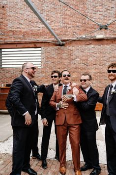 a group of men standing next to each other wearing suits and ties with sunglasses on