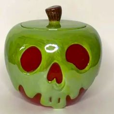 a green apple shaped like a skull with red eyes