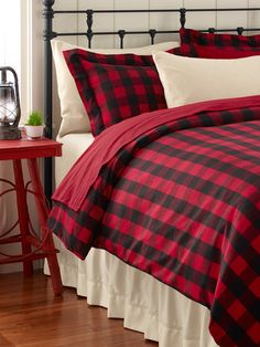 a red and black plaid comforter set on a bed in a room with wood floors