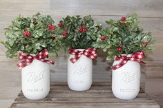 three white mason jars with red bows and holly