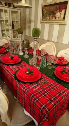 the table is set for christmas dinner with red plates and green napkins on it