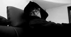 a man wearing glasses and a hoodie sitting on a couch