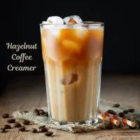 a tall glass filled with liquid and ice cream on top of a wooden table next to coffee beans