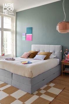 a bedroom with blue walls and wooden flooring has a large bed in the middle