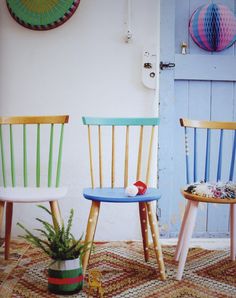 two wooden chairs sitting next to each other in front of a blue door and potted plant